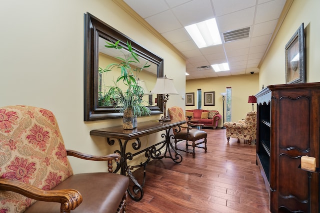 sitting room with a drop ceiling and dark hardwood / wood-style floors