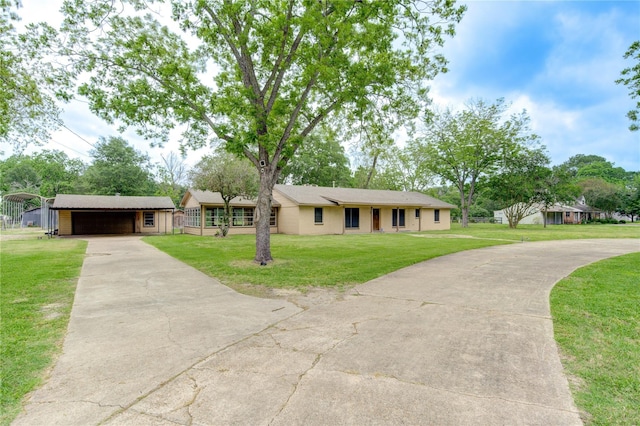 single story home with an outbuilding, a garage, a front yard, and a carport