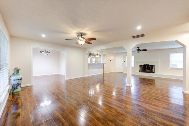 unfurnished living room featuring a textured ceiling, ceiling fan with notable chandelier, and dark hardwood / wood-style floors