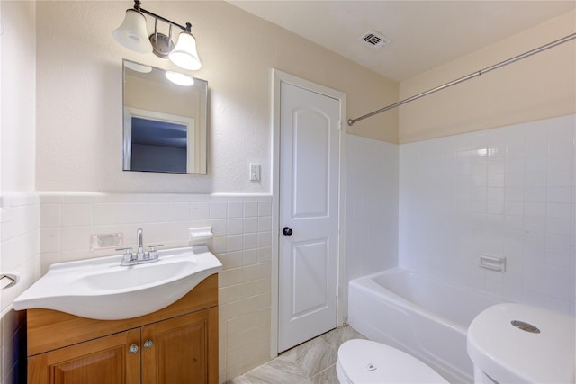 full bathroom with vanity, toilet, tile walls, and tiled shower / bath