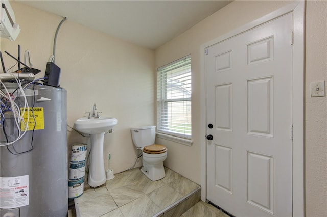 bathroom featuring gas water heater, toilet, and sink