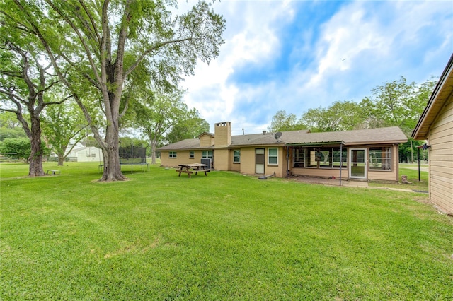 view of yard with a sunroom and a trampoline