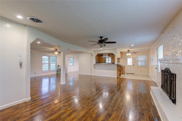 unfurnished living room featuring a fireplace, wood-type flooring, and ceiling fan