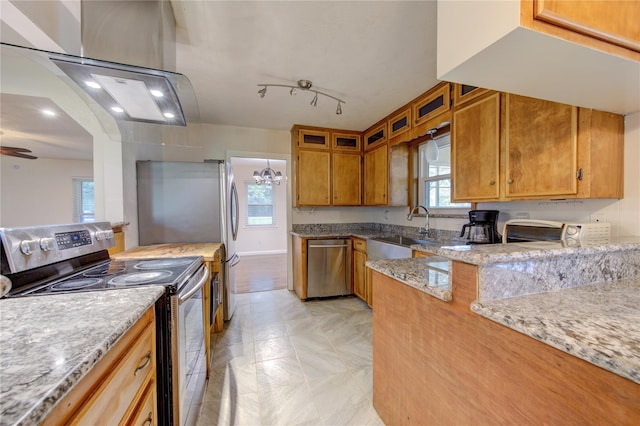 kitchen with ceiling fan with notable chandelier, light stone counters, sink, and appliances with stainless steel finishes