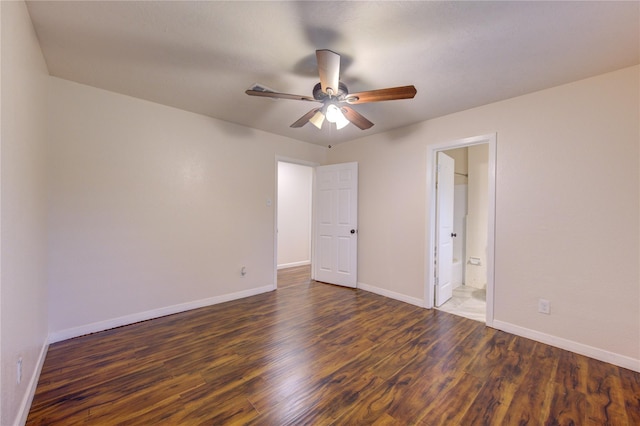 unfurnished bedroom featuring ensuite bath, ceiling fan, and dark wood-type flooring