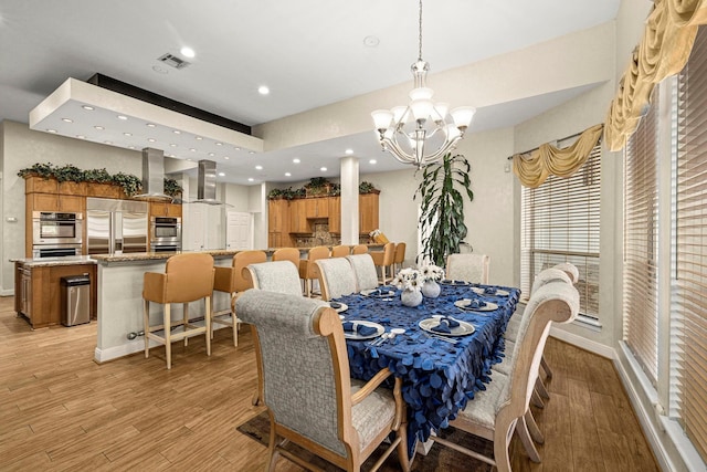 dining room with an inviting chandelier and light hardwood / wood-style flooring