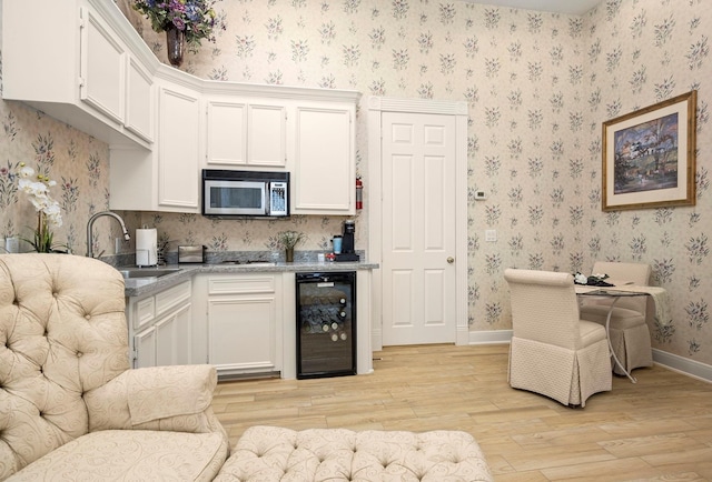 kitchen with white cabinetry, sink, beverage cooler, and light wood-type flooring