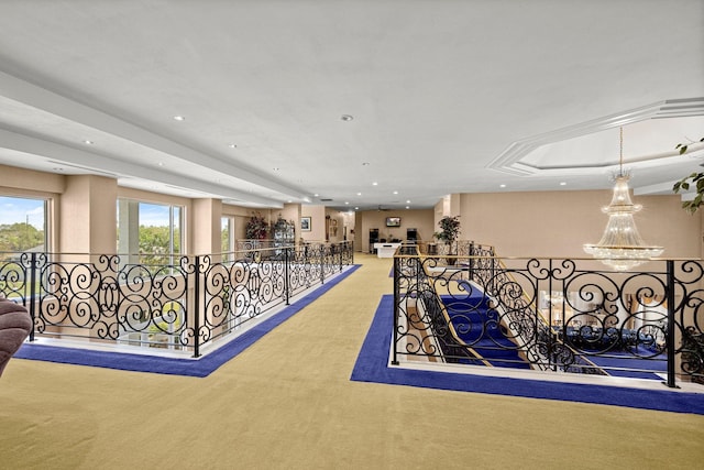 interior space with a tray ceiling, carpet floors, and an inviting chandelier