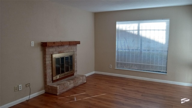 unfurnished living room featuring hardwood / wood-style flooring and a brick fireplace