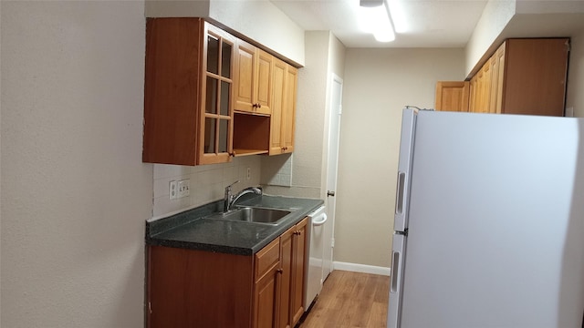 kitchen featuring dishwasher, sink, decorative backsplash, light hardwood / wood-style floors, and white fridge