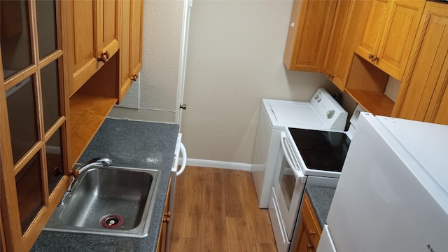 washroom with hardwood / wood-style floors, washer and dryer, and sink