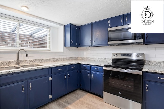 kitchen with blue cabinetry, sink, stainless steel appliances, and light hardwood / wood-style floors