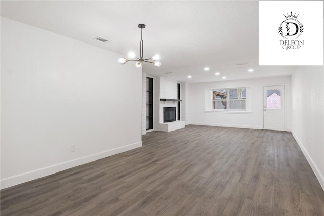 unfurnished living room with a fireplace, dark hardwood / wood-style floors, and a notable chandelier