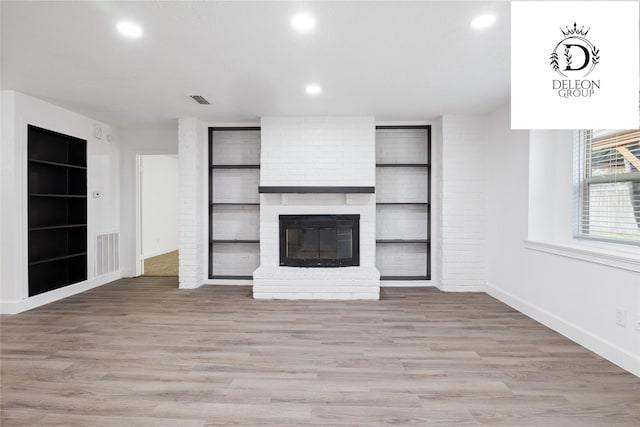 unfurnished living room featuring light hardwood / wood-style flooring and a brick fireplace