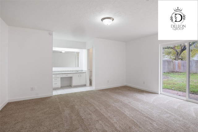 carpeted spare room with built in desk and a textured ceiling