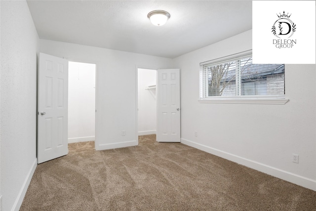 unfurnished bedroom featuring a walk in closet, light carpet, and a closet