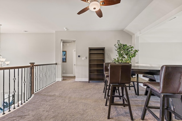 carpeted dining area with ceiling fan and vaulted ceiling