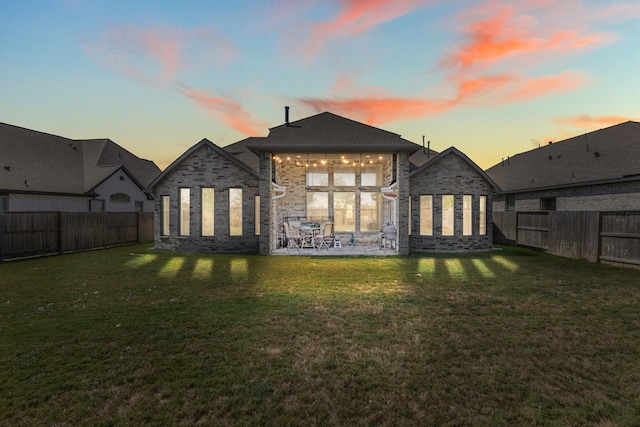 back house at dusk with a patio area and a yard