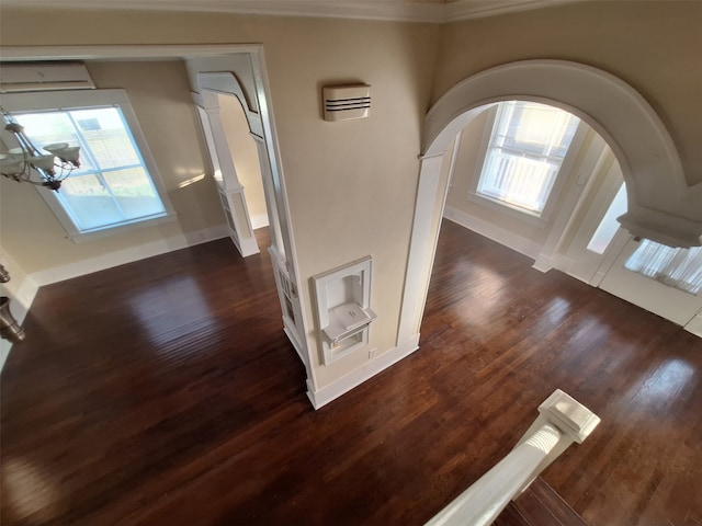 interior space with dark hardwood / wood-style floors, a wall unit AC, and an inviting chandelier