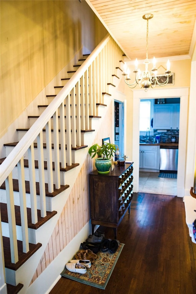 staircase featuring sink, a chandelier, wooden walls, wood ceiling, and hardwood / wood-style flooring