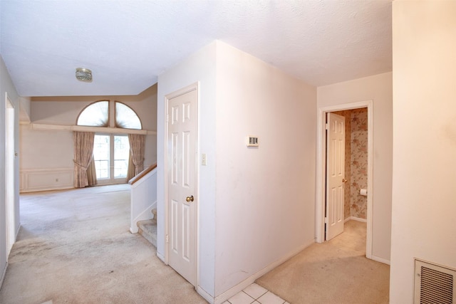 hallway with light carpet and a textured ceiling