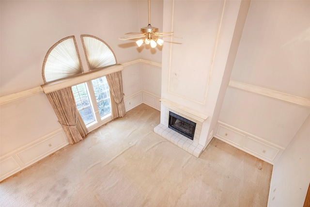 unfurnished living room featuring ceiling fan, a fireplace, and light carpet