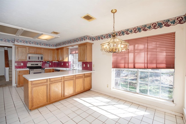 kitchen with an inviting chandelier, decorative backsplash, decorative light fixtures, stainless steel range oven, and kitchen peninsula