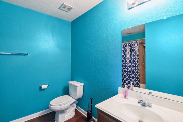 bathroom with hardwood / wood-style floors, vanity, a textured ceiling, and toilet