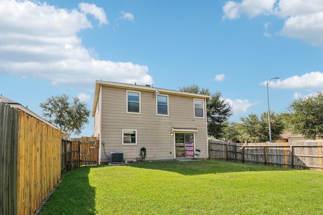 back of house featuring central air condition unit and a yard