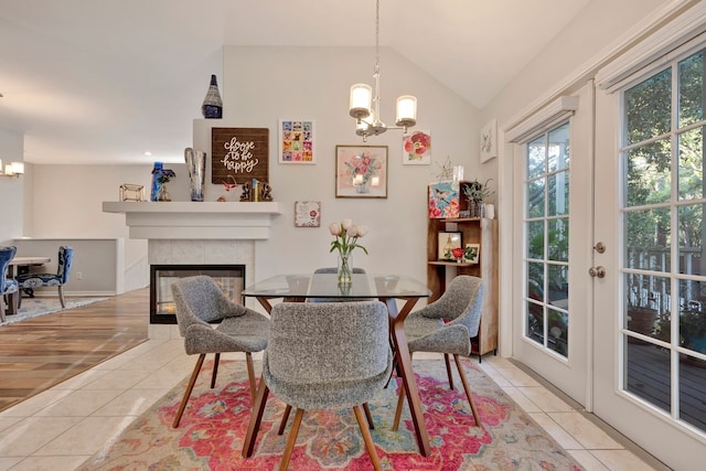 tiled dining room featuring a fireplace, french doors, an inviting chandelier, and vaulted ceiling