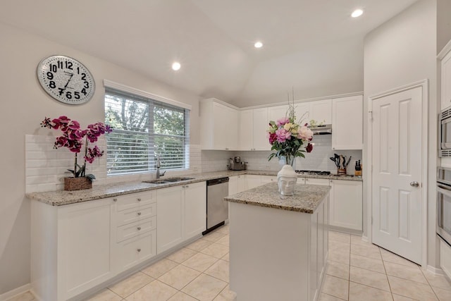 kitchen featuring light stone counters, stainless steel appliances, sink, white cabinetry, and a kitchen island