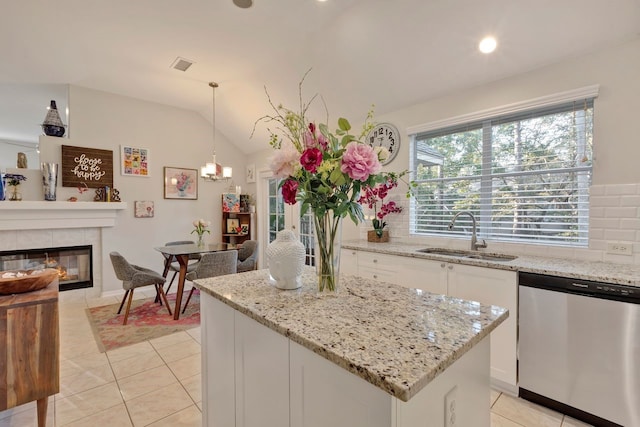 kitchen with white cabinets, sink, vaulted ceiling, stainless steel dishwasher, and decorative light fixtures