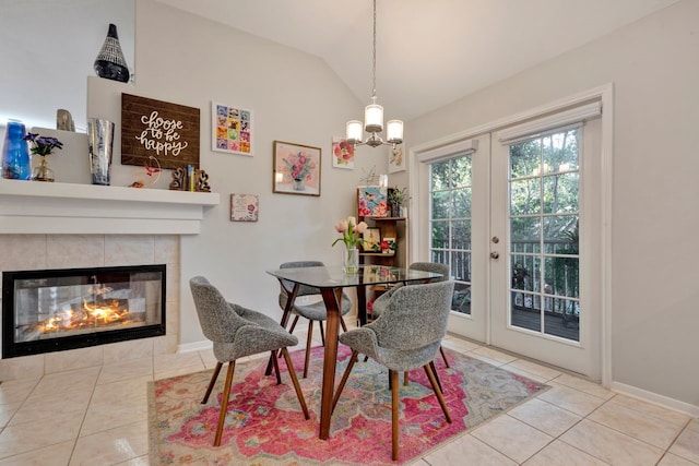 dining area featuring a tile fireplace, light tile patterned floors, french doors, and lofted ceiling