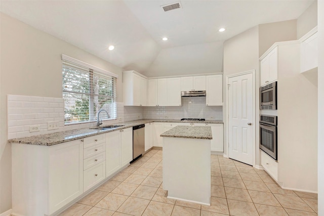 kitchen featuring sink, a center island, light stone counters, white cabinets, and appliances with stainless steel finishes