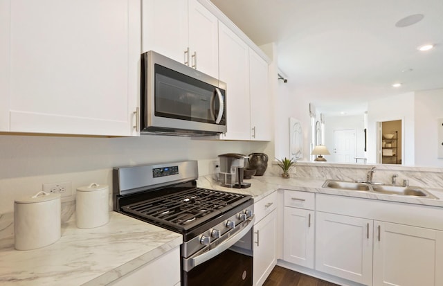 kitchen with white cabinetry, sink, light stone counters, dark hardwood / wood-style flooring, and appliances with stainless steel finishes