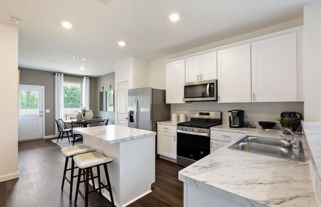 kitchen with sink, a center island, dark hardwood / wood-style flooring, white cabinets, and appliances with stainless steel finishes