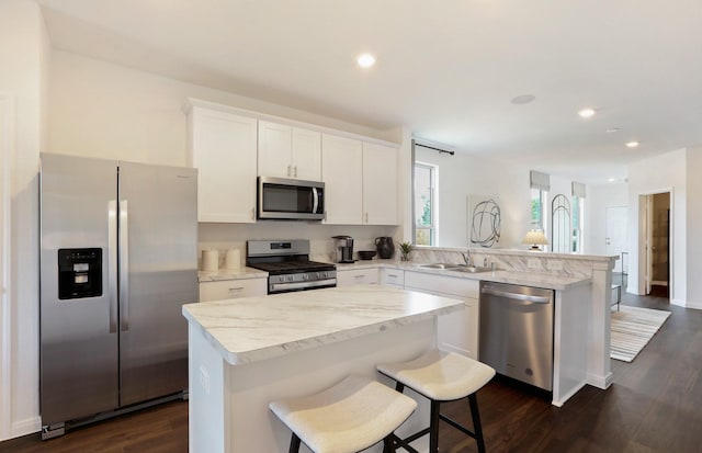 kitchen with kitchen peninsula, stainless steel appliances, a kitchen island, and sink