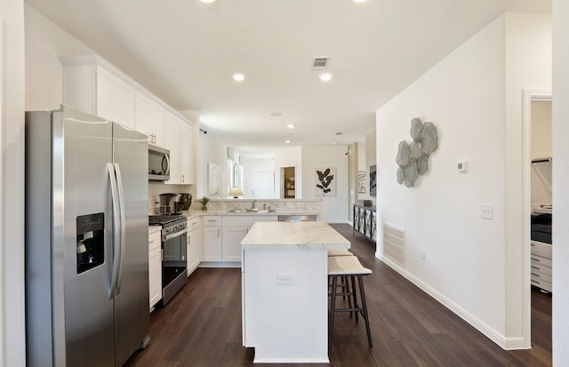 kitchen featuring a center island, white cabinets, a breakfast bar area, kitchen peninsula, and stainless steel appliances