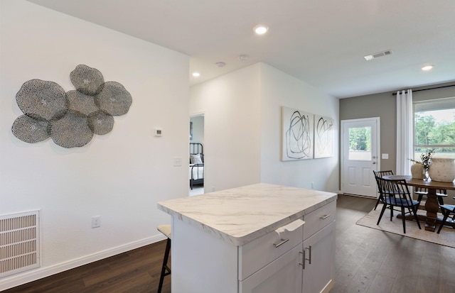 kitchen with dark hardwood / wood-style floors, a kitchen island, and a breakfast bar