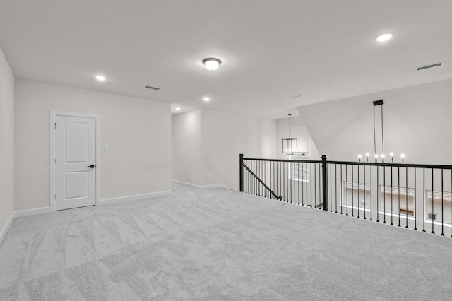 carpeted empty room featuring a notable chandelier