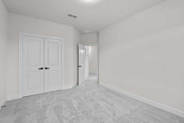 unfurnished bedroom with light colored carpet and a closet