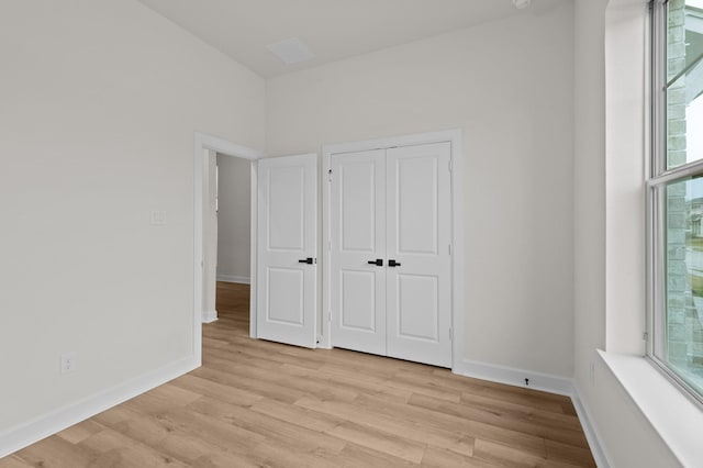 unfurnished bedroom featuring multiple windows, a closet, and light hardwood / wood-style floors