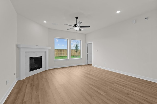 unfurnished living room featuring ceiling fan, a fireplace, and light wood-type flooring