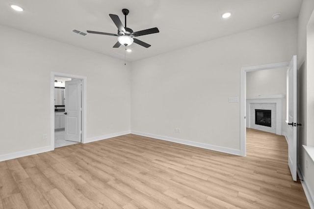 interior space with ensuite bathroom, light hardwood / wood-style flooring, ceiling fan, and a premium fireplace