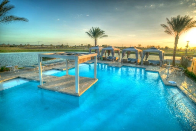 pool at dusk featuring a gazebo