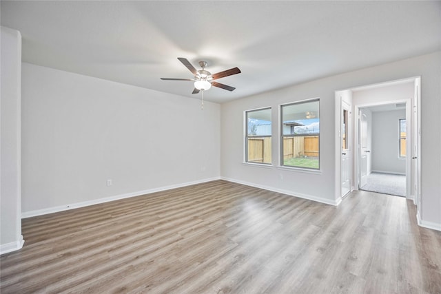 empty room with ceiling fan and light hardwood / wood-style flooring