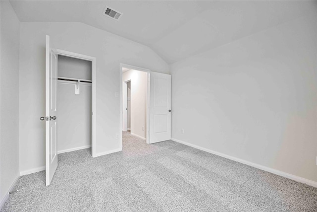 unfurnished bedroom with a closet, light colored carpet, and vaulted ceiling