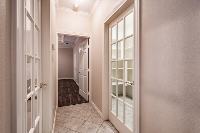 corridor with light tile patterned flooring, a textured ceiling, and ornamental molding