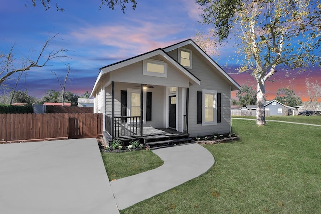 bungalow-style home with ceiling fan and a yard