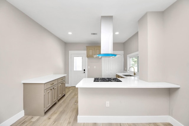 kitchen with sink, gas stovetop, kitchen peninsula, island exhaust hood, and light hardwood / wood-style floors